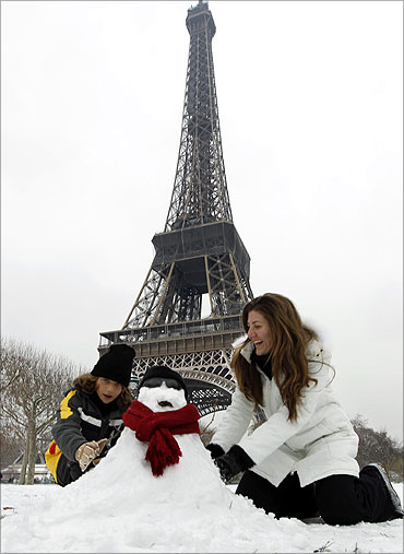 tourists from Sao Paulo enjoy to make a snowman in front the Eiffel Tower in Paris.