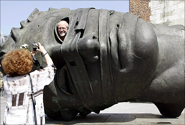 Tourists take a picture with a sculpture by Igor Mitoraj in central Krakow, southern Poland.
