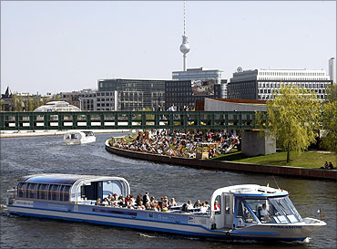 Tourist vessels make their way during a sunny day on the Spree river in Berlin.