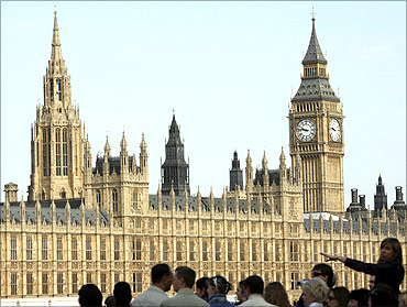 Tourists look at the Houses of Parliament from the south bank of the River Thames, in central London.