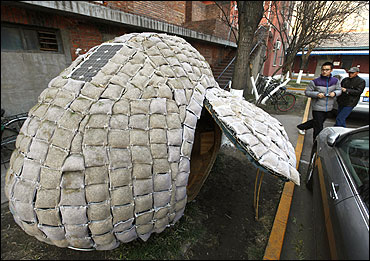 Visitors take photos of an egg-shaped mobile house near its owner Dai Haifei's office building in Beijing.