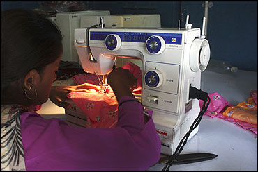 A woman sews clothes on a sewing machine driven by solar energy in Ahmedabad.