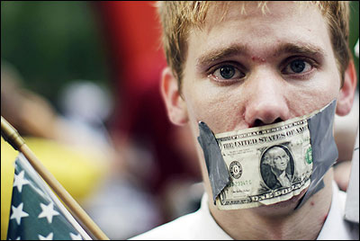 A demonstrator from the Occupy Wall Street campaign stands with a dollar taped over his mouth as he stands in Zucotti Park.