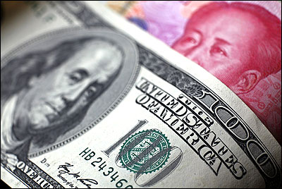 A Chinese 100 yuan banknote is placed under a $100 banknote.
