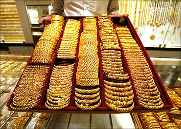 A salesman displays a tray of gold bangles.