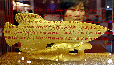A woman looks at a golden fish displayed during the China International Jewellery Fair in Beijing.