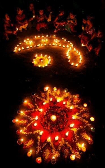 Children sit beside lighted lamps during the celebrations on the eve of the Hindu festival of Diwali.