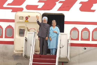 Prime Minister Singh, with his wife Gursharan Kaur by his side, waves to the crowd as they exit the aircraft.