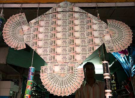 An kite maker stands besides a kite made of notes of the Indian currency in New Delhi.