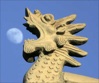 Chinese architecture style dragon head is seen as the moon rises at Jiayuguan Pass, China.