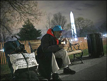 A homeless man sits on a bench with a cup of chili that he received from the Salvation Army in Washington.