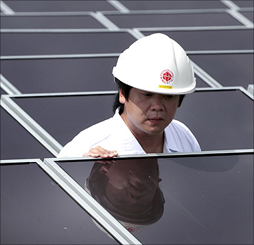 A worker checks solar panels on the roof of a building in Hong Kong Electric Lamma island power unit