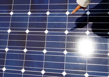 A worker checks solar panels at a solar power field in Kawasaki.