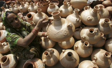 A vendor sells earthen water pots at her roadside shop on a hot day in Chandigarh.