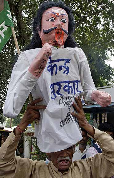 A worker of Samajwadi Party carries an effigy depicting the central government on his head during a protest against a price hike.