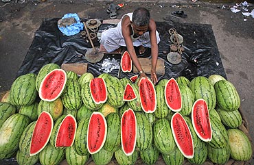 A vendor arranges watermelons for sale along the side of a road in Kolkata.