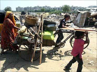 A family carries their belongings in a cycle rickshaw after they salvaged them from the debris of demolished shanties.
