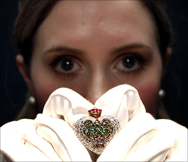Jessica Wyndham, a trainee specialist in Sotheby's jewellery department, holds a ruby, diamond and emerald brooch by Cartier.