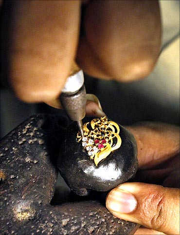 A jeweller sets stones in a gold pendant at a workshop in Lahore.