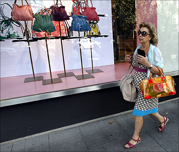 A woman walks past a shop window in a designer shopping area known for its luxurious shops in central Madrid.