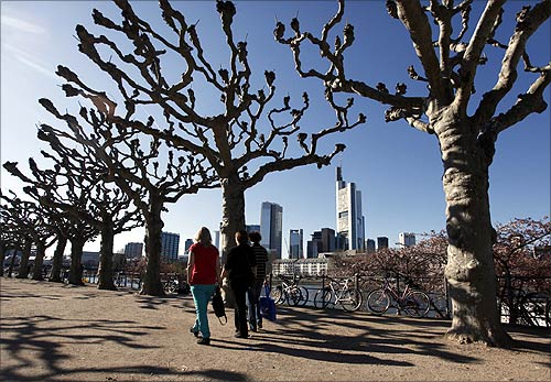 Pedestrians enjoy the sun and warm weather during a walk along the river Main in Frankfurt.