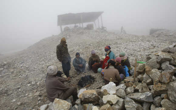 Workers warm themselves around a fire on a cold foggy day at a stone crusher plant in Tawang in Arunachal Pradesh.