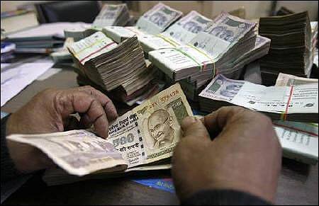 An employee counts Indian rupee notes at a cash counter inside a bank in Tripura.