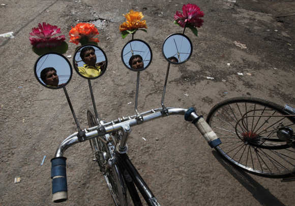 A rickshaw puller is reflected on the installed mirrors of his rickshaw as he waits for passengers on a street in Patna.