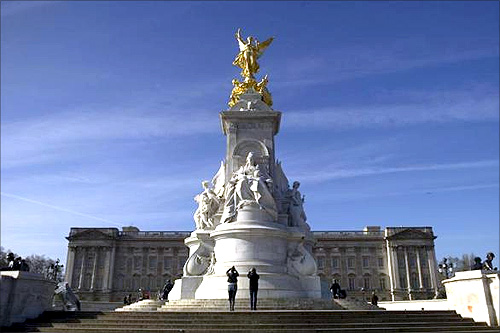 Tourists photograph the Queen Victoria Monument outside Buckingham Palace in London.