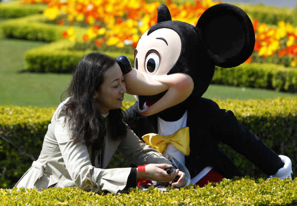 A visitor is kissed by Disney character Mickey Mouse at Tokyo Disneyland in Urayasu, east of Tokyo.