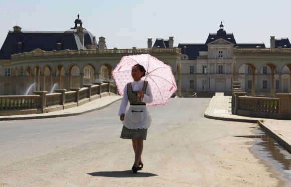 A waitress carrying an umbrella walks down the driveway to Chateau Laffitte Hotel located on the outskirts of Beijing.