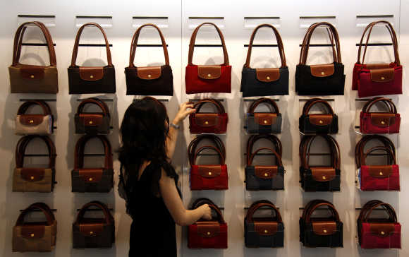 A worker at a store for French luxury goods maker Longchamp adjusts a display of bags in central Beijing.