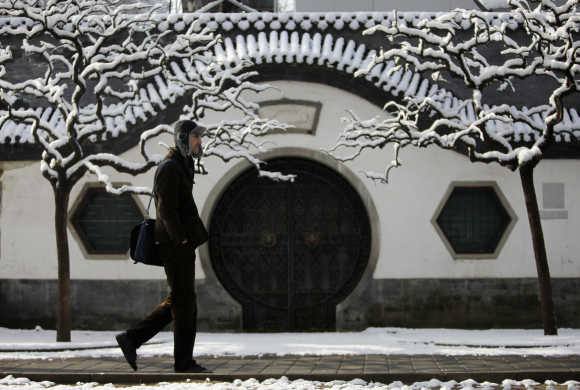 A man walks past a Beijing traditional gate covered in snow at Ritan Park in central Beijing.