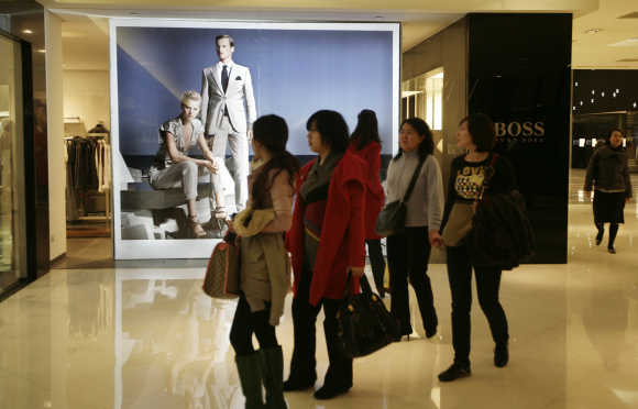 Women walk past a Hugo Boss store at a shopping mall in Beijing.