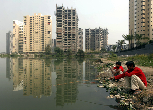 Labourers fish in a pond near a residential estate under construction in Kolkata.
