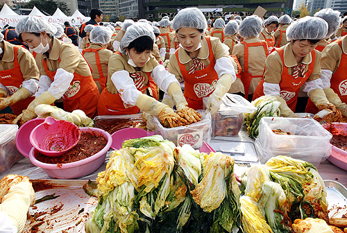 Women make traditional Korean side dish kimchi, or fermented cabbage, at a charity event at the Seoul City Hall Plaza.