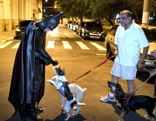 Retired Brazilian police officer Andre Luiz Pinheiro, 50, dressed as super-hero Batman, is greeted by a dog in Taubate city, Sao Paulo.