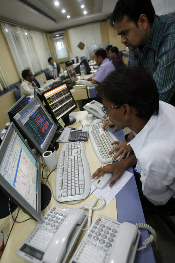 Traders look at their computer screens while trading at a stock brokerage firm in Mumbai.