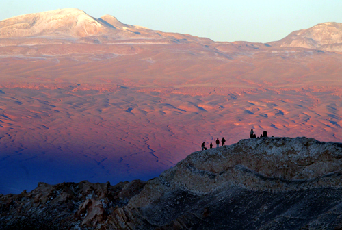 Tourists rest above a hill in Valle de la Luna (Moon Valley) located inside the nature reserve of Los Flamencos in the Atacama Desert, near San Pedro de Atacama in northern Chile.