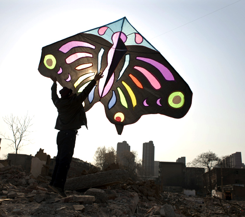 A man holds up a kite as he helps to fly it at a demolition site near residential areas in Shijiazhuang, Hebei province.