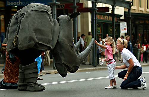A street performer in a rhinoceros costume jokes with a little girl and her mother in Sydney prior to the start of a rugby match between France and New Zealand.