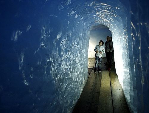 Visitors look at the walls of an ice cave at Rhone glacier in the Swiss Alps at the Furkapass.