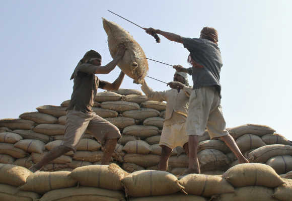 Workers lift a sack of rice to load onto a truck at a wholesale grain market in Chandigarh.