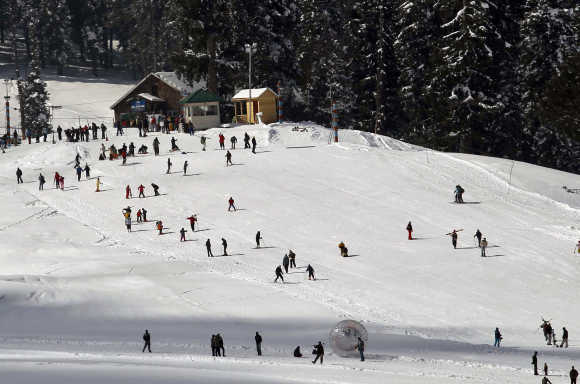 Tourists and skiers ski on a slope in Gulmarg.