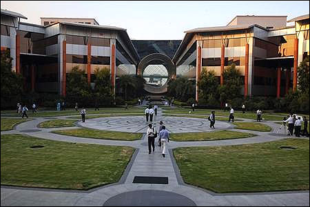 Employees walk in front of a building dubbed the ''washing machine'', a well-known landmark built by Infosys at the Electronics City, Bangalore.