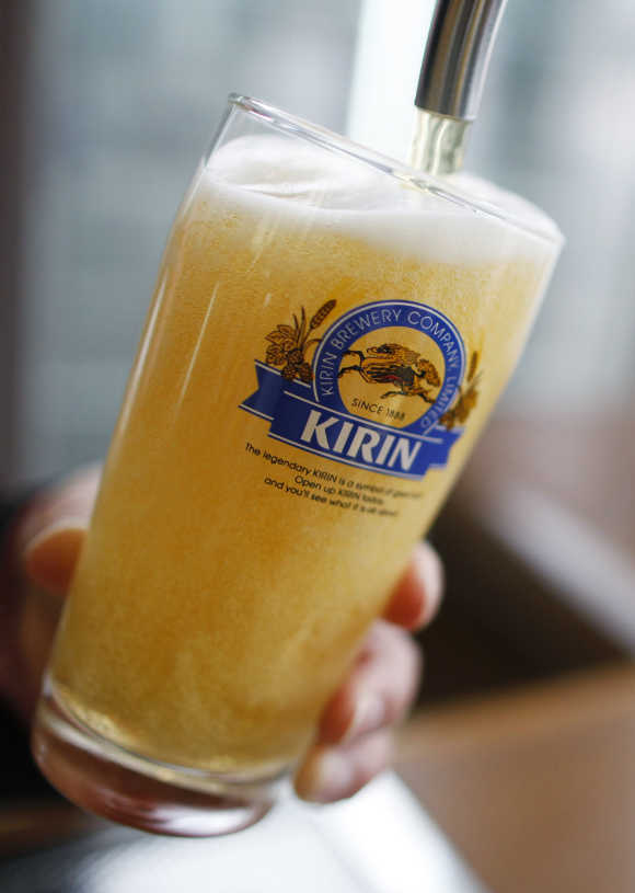 An employee of Kirin Brewery Co fills a glass with Kirin Beer at a tasting room of the company's factory in Sendai, Japan.