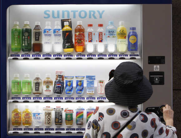A woman purchases Suntory beverage from a vending machine in Tokyo.