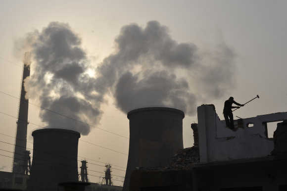 A labourer works near cooling towers of a power plant.