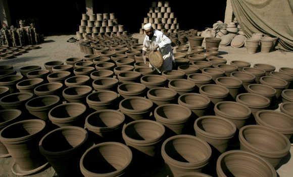 A man holds a clay plate to put under wet pots, used for plants, at his make-shift factory in Peshawar.