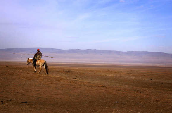 A herder rides a horse as he tends his animals on grasslands located around 200km south-west of the Mongolian capital city Ulan Bator.